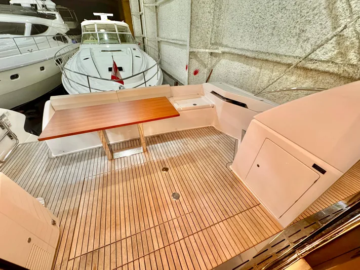 Time To Fly Yacht Photos Pics 2022 Ferretti Yachts 550 deck with wooden table, docked in a marina.