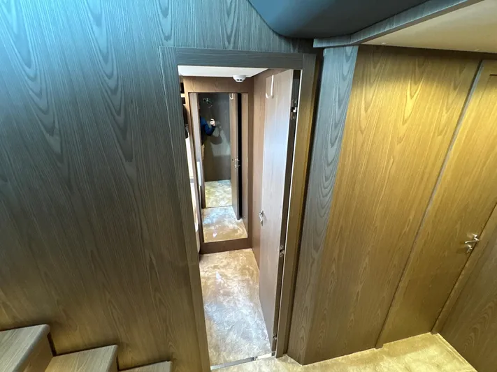 Time To Fly Yacht Photos Pics Interior hallway of 2022 Ferretti Yachts 550, featuring wood paneling and carpeted flooring.