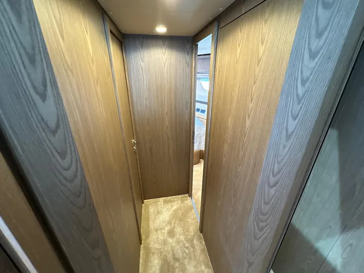 Time To Fly Yacht Photos Pics Interior hallway of 2022 Ferretti Yachts 550, featuring wood paneling and carpet flooring.