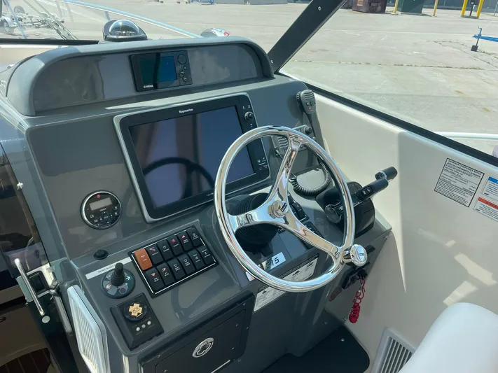  Yacht Photos Pics Control panel of a 2012 Pursuit OS 315 Offshore boat with steering wheel and navigation equipment.