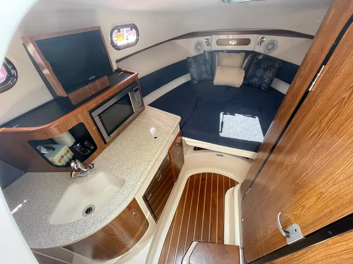  Yacht Photos Pics 2012 Pursuit OS 315 Offshore cabin interior with kitchenette and cozy sleeping area.