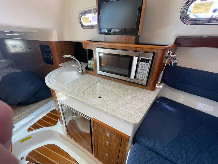  Yacht Photos Pics 2012 Pursuit OS 315 Offshore boat interior with kitchenette, microwave, and seating area.