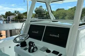  Yacht Photos Pics 2021 Yellowfin 39 boat dashboard with Garmin navigation system, docked near lush greenery.