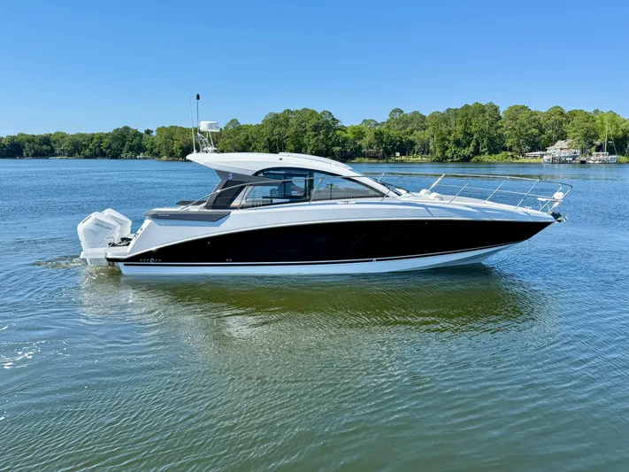  Yacht Photos Pics 2025 Beneteau Gran Turismo 36 yacht on a serene lake with lush green shoreline.