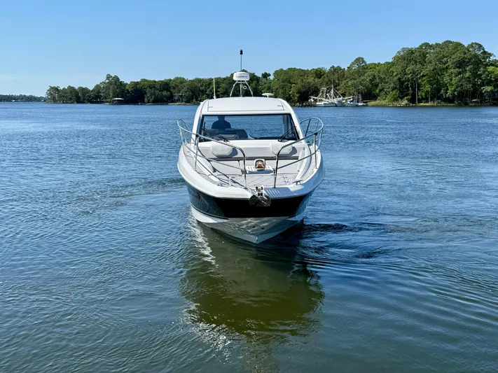  Yacht Photos Pics 2025 Beneteau Gran Turismo 36 cruising on a serene lake with lush green shoreline.