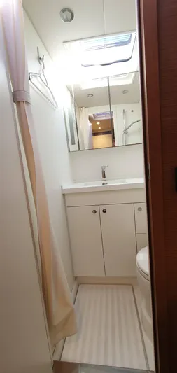 Aida II Yacht Photos Pics Compact yacht bathroom with white cabinetry, mirror, and shower curtain, CNB 66, 2018 model.