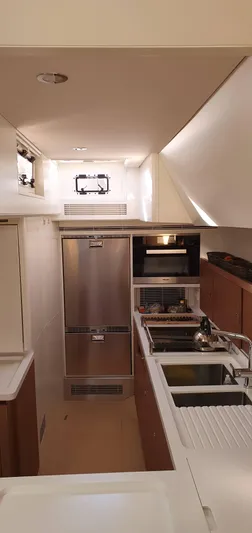 Aida II Yacht Photos Pics Modern yacht kitchen interior with stainless steel appliances, wooden cabinetry, and sleek design. CNB 66, 2018.