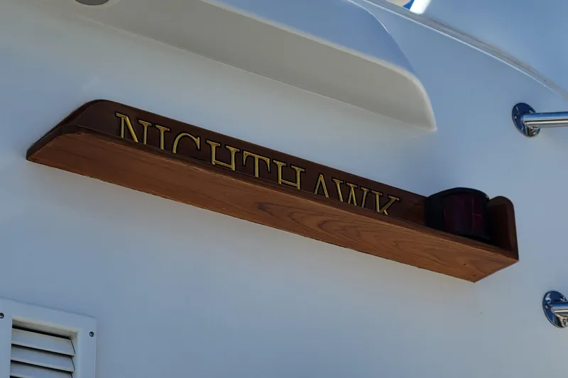 Nighthawk Yacht Photos Pics Nameplate "NIGHTHAWK" on 1999 Lyman-Morse pilothouse boat, wooden design with light.