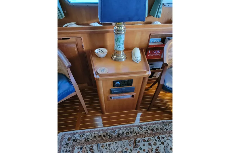 Nighthawk Yacht Photos Pics 1999 Lyman-Morse pilothouse interior with lamp, phone, and books on wooden furniture.
