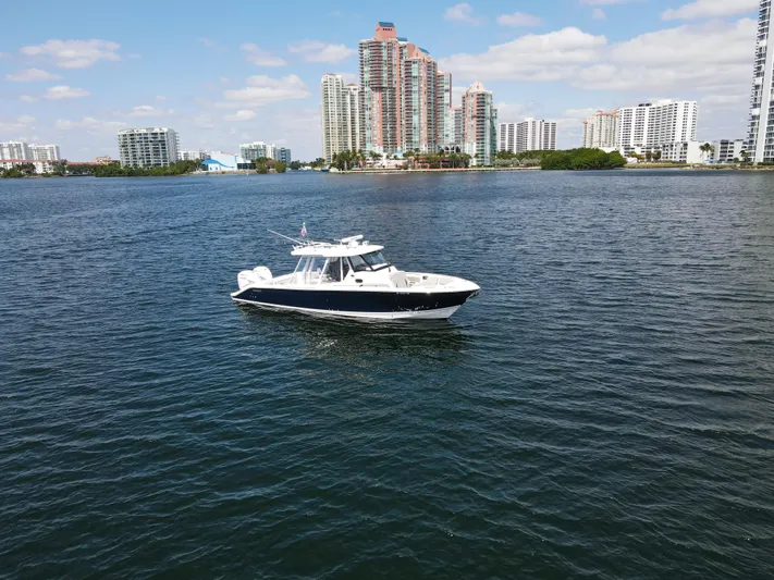  Yacht Photos Pics 2022 Pursuit S 358 Sport boat on water with city skyline background.