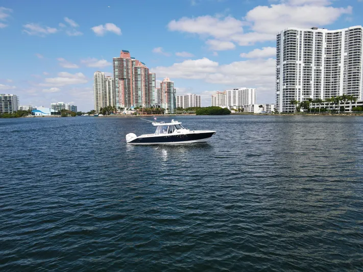  Yacht Photos Pics 2022 Pursuit S 358 Sport boat on water with city skyline in background.