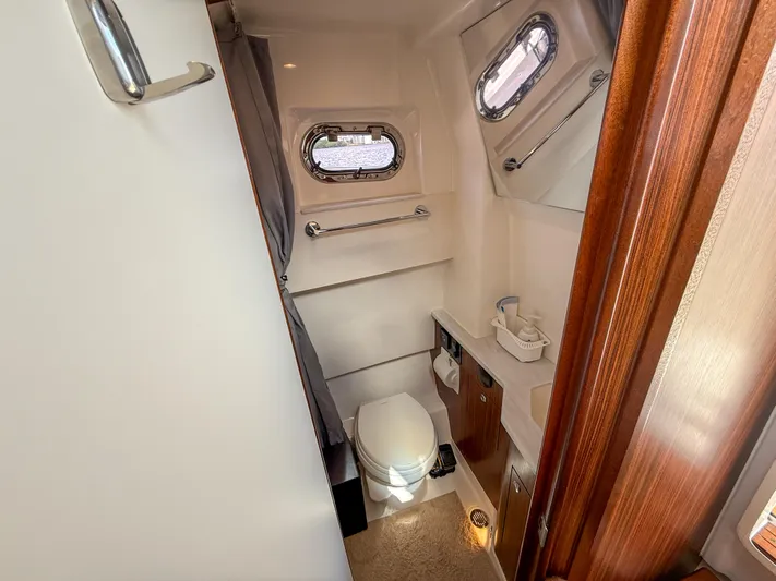  Yacht Photos Pics 2022 Pursuit S 358 Sport boat bathroom with portholes, toilet, and sink.