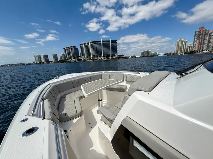  Yacht Photos Pics 2022 Pursuit S 358 Sport boat with seating area, city skyline, and blue sky.