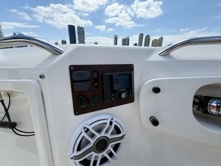  Yacht Photos Pics 2022 Pursuit S 358 Sport boat dashboard with controls and speaker, city skyline in background.