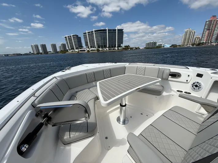  Yacht Photos Pics 2022 Pursuit S 358 Sport boat interior with seating and table, city skyline in background.