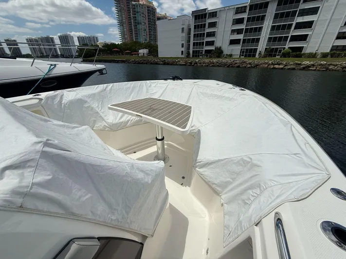  Yacht Photos Pics 2022 Pursuit S 358 Sport boat with covered seating and table, docked near waterfront buildings.