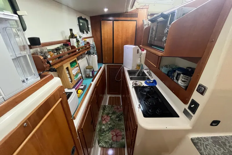  Yacht Photos Pics Compact galley kitchen in 2004 PDQ Passage Maker boat with wooden cabinetry and modern appliances.