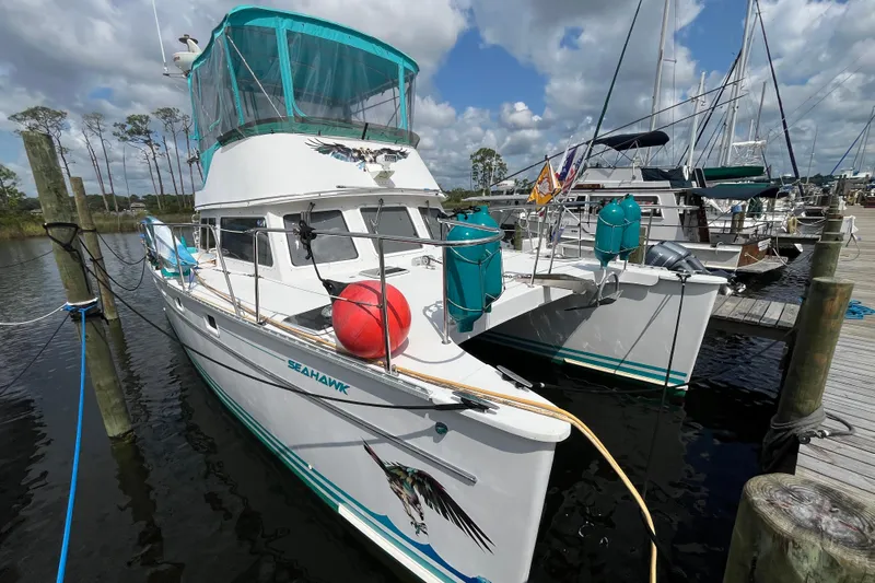 Yacht Photos Pics 2004 PDQ Passage Maker catamaran docked, featuring teal accents and a clear sky backdrop.