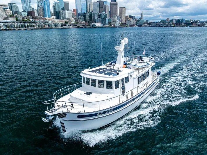 Speakeasy Yacht Photos Pics Nordic Tug 54 (2007) cruising near a city skyline on a clear day.