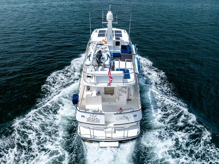 Speakeasy Yacht Photos Pics Nordic Tug 54 (2007) cruising on open water, rear view with wake.