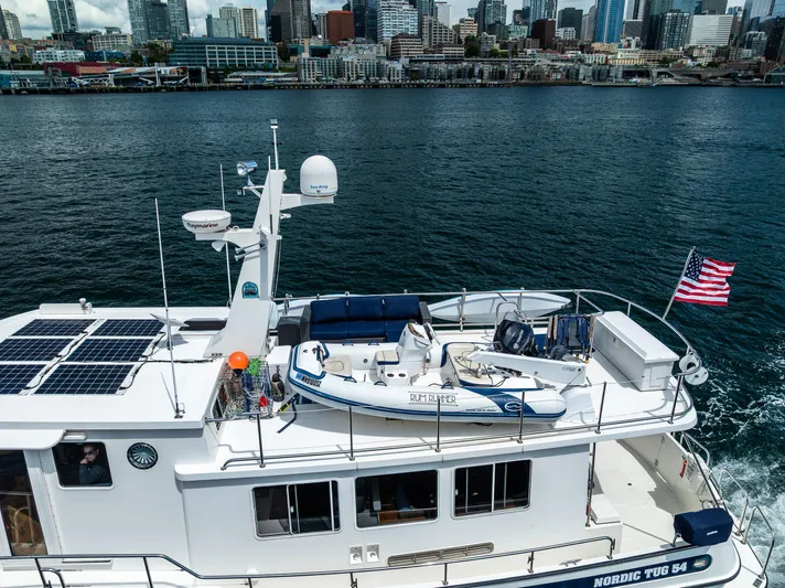 Speakeasy Yacht Photos Pics Nordic Tug 54 yacht cruising near city skyline, featuring solar panels and American flag.