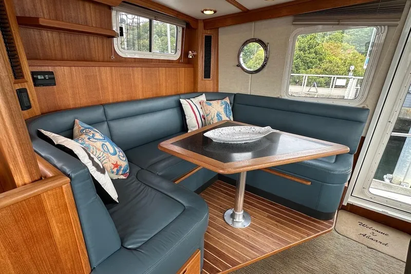 Speakeasy Yacht Photos Pics Cozy dining area in 2007 Nordic Tug 54 with blue seating and wooden accents.