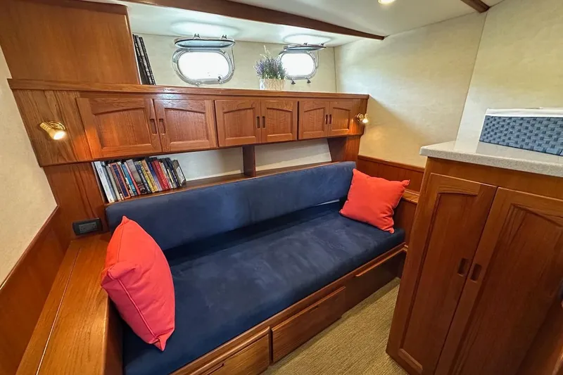 Speakeasy Yacht Photos Pics Cozy interior of 2007 Nordic Tug 54 with blue sofa, red pillows, and wooden cabinetry.