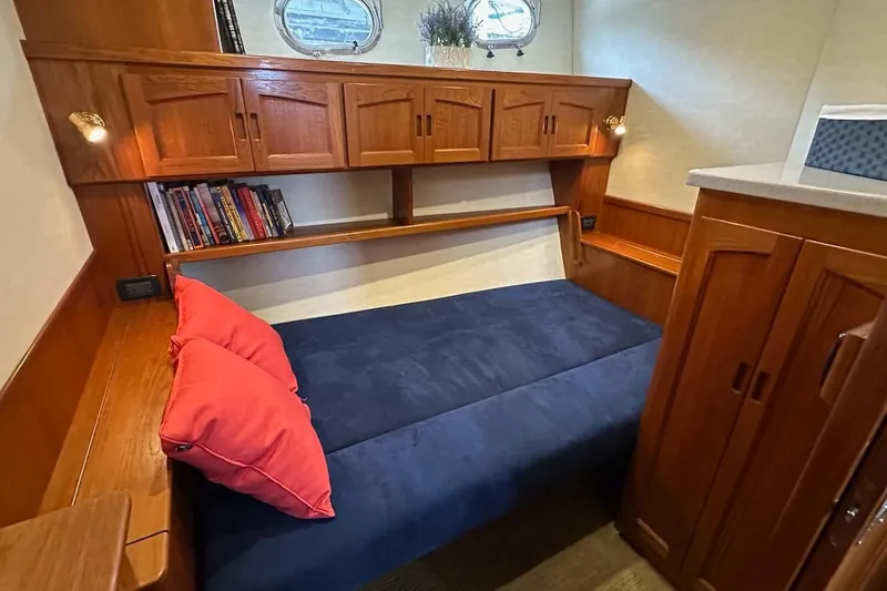 Speakeasy Yacht Photos Pics Cozy cabin interior of 2007 Nordic Tug 54 with wooden cabinetry and blue bedding.
