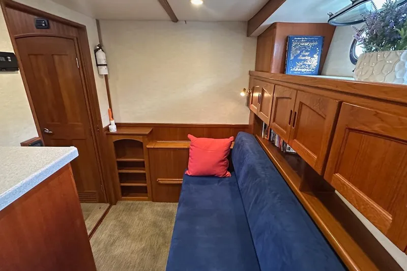 Speakeasy Yacht Photos Pics Cozy interior of 2007 Nordic Tug 54 with blue sofa, wooden cabinets, and decorative elements.