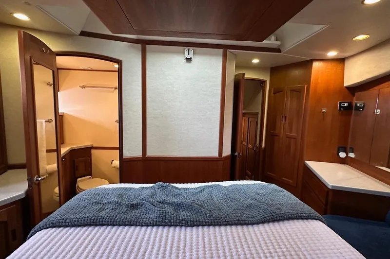 Speakeasy Yacht Photos Pics Luxurious 2007 Nordic Tug 54 interior cabin with bed, bathroom, and wooden cabinetry.