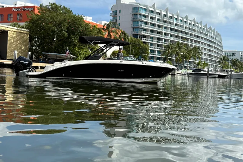  Yacht Photos Pics 2021 Sea Ray SDX 290 Outboard boat on calm water near modern buildings.