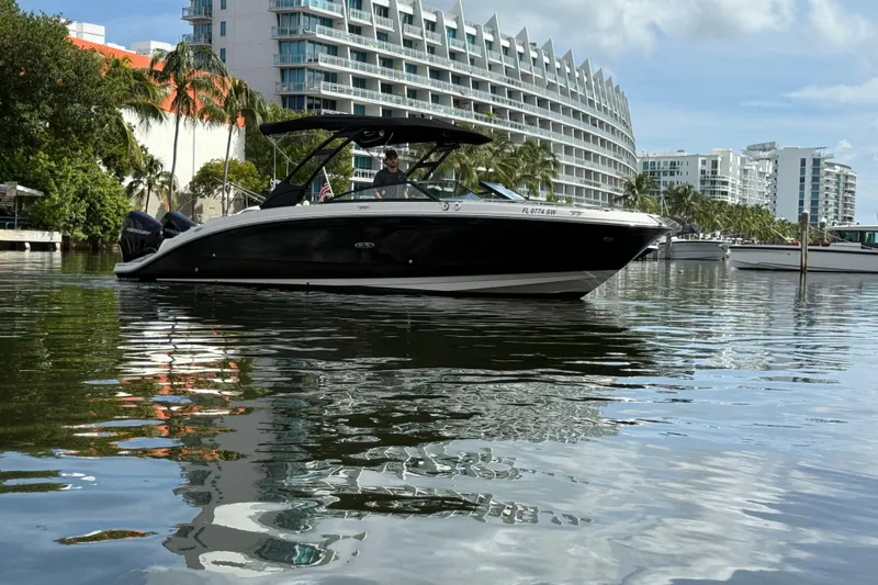  Yacht Photos Pics 2021 Sea Ray SDX 290 Outboard boat on water near modern buildings and palm trees.