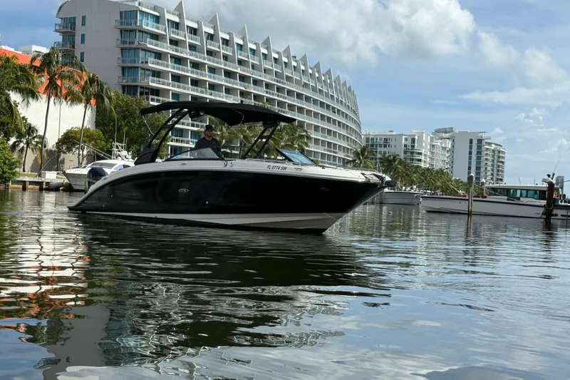 Yacht Photos Pics 2021 Sea Ray SDX 290 Outboard boat on water near modern buildings and palm trees.