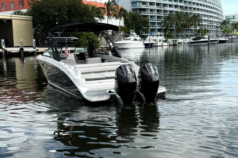  Yacht Photos Pics 2021 Sea Ray SDX 290 Outboard boat docked in a marina with modern buildings.