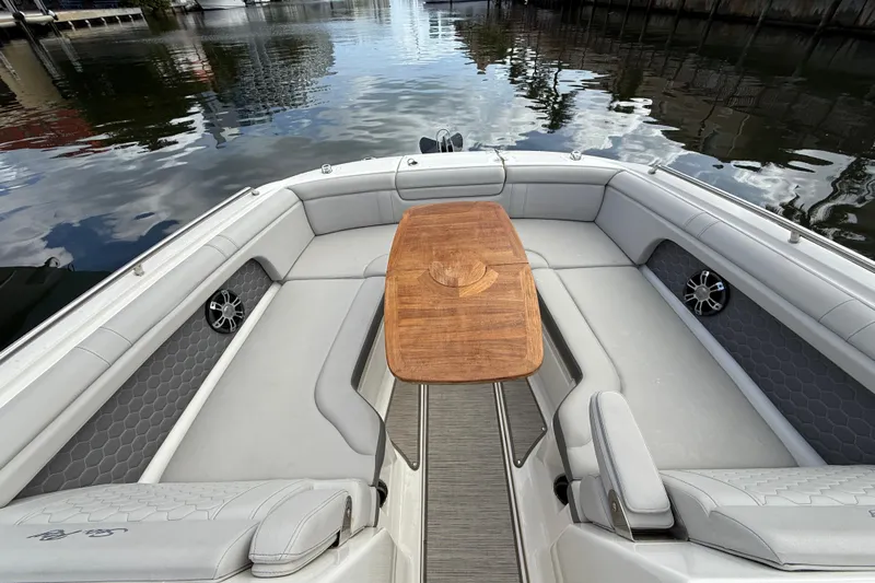  Yacht Photos Pics 2021 Sea Ray SDX 290 Outboard boat interior with wooden table and cushioned seating.