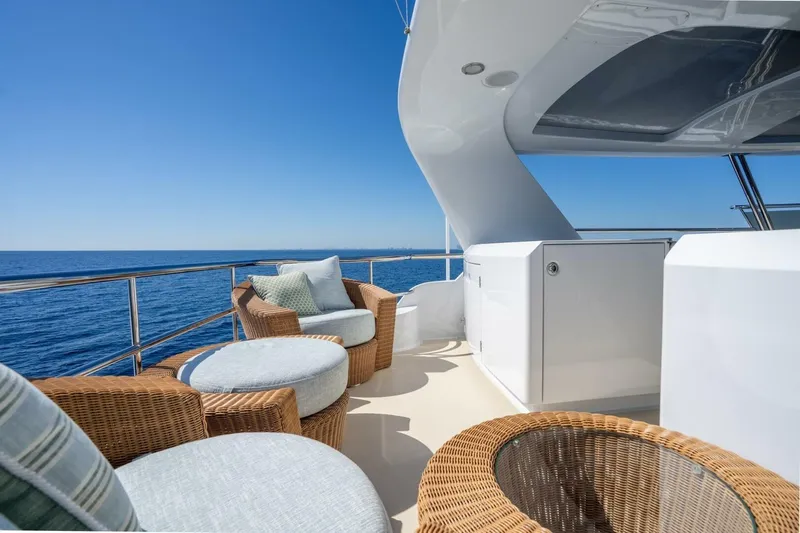 Ruffian Yacht Photos Pics Luxurious Delta Marine Tri-Deck yacht deck with wicker seating, ocean view, and clear blue sky.