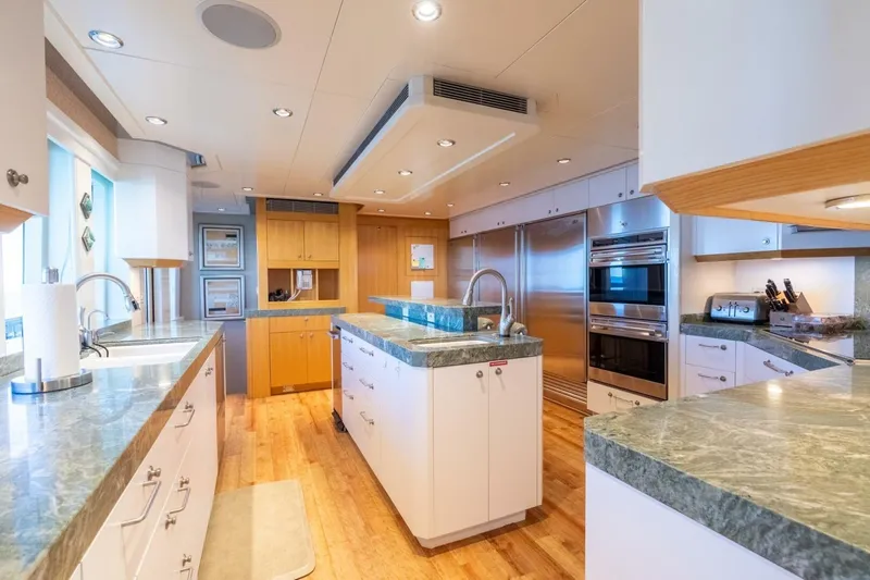 Ruffian Yacht Photos Pics Luxurious kitchen interior on 2001 Delta Marine Tri-Deck yacht with modern appliances and marble countertops.