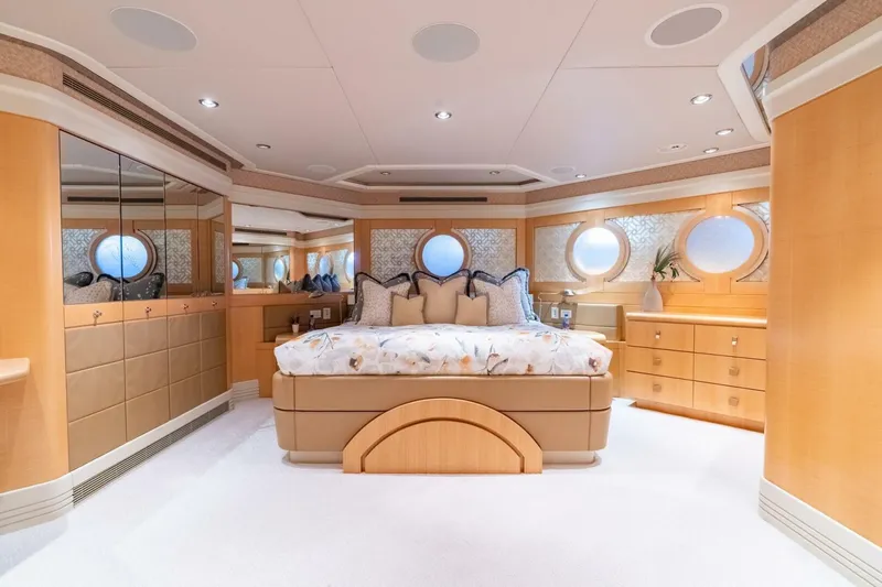 Ruffian Yacht Photos Pics Luxurious bedroom interior on 2001 Delta Marine Tri-Deck yacht, featuring elegant wood finishes and round windows.