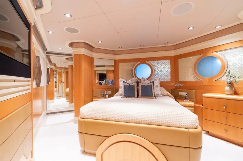 Ruffian Yacht Photos Pics Luxurious bedroom interior on 2001 Delta Marine Tri-Deck yacht, featuring elegant wood finishes and round windows.