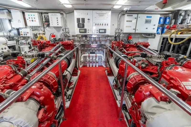 Ruffian Yacht Photos Pics Engine room of 2001 Delta Marine Tri-Deck yacht with red machinery and control panels.