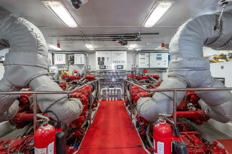 Ruffian Yacht Photos Pics Engine room of 2001 Delta Marine Tri-Deck yacht with red machinery and fire extinguishers.
