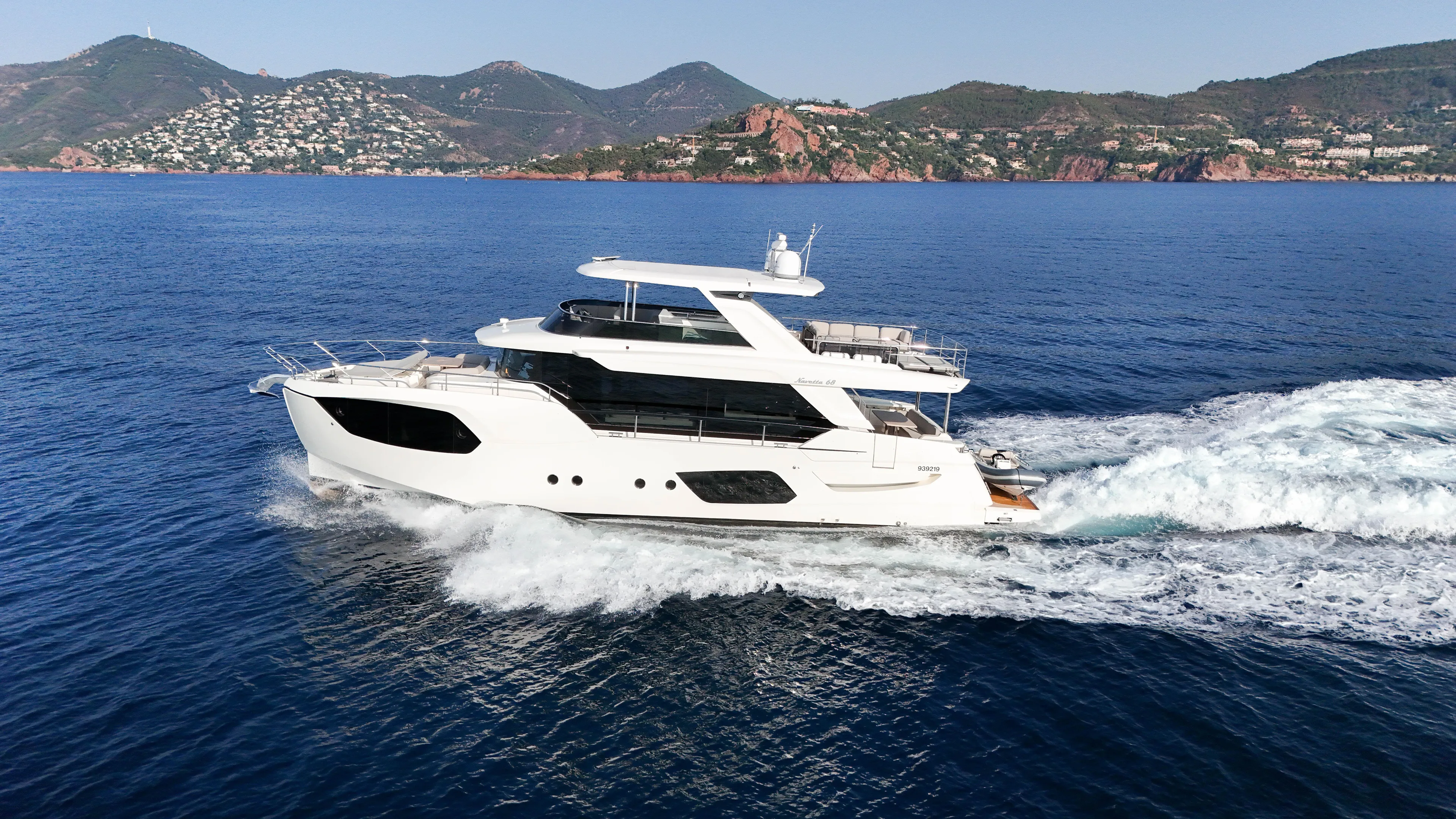  Yacht Photos Pics 2023 Absolute Navetta 68 yacht cruising on blue ocean with scenic coastal backdrop.