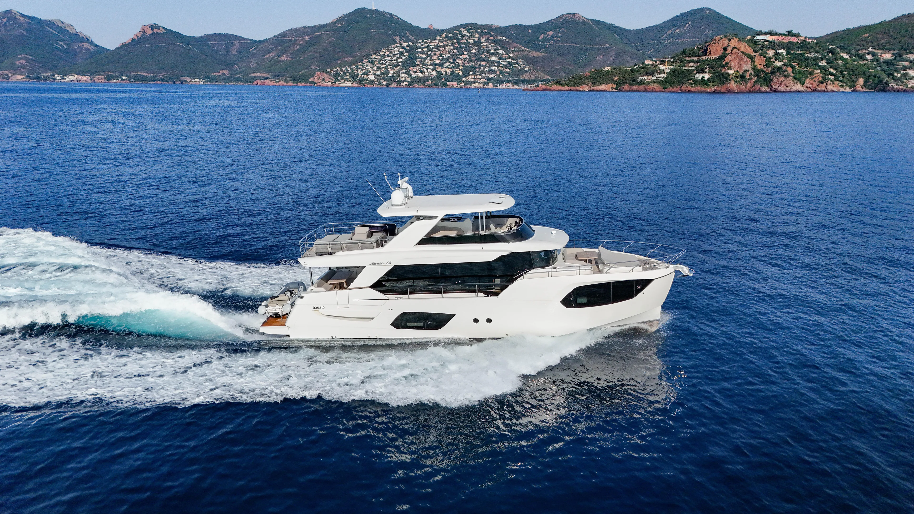  Yacht Photos Pics 2023 Absolute Navetta 68 yacht cruising on blue ocean with scenic mountain backdrop.