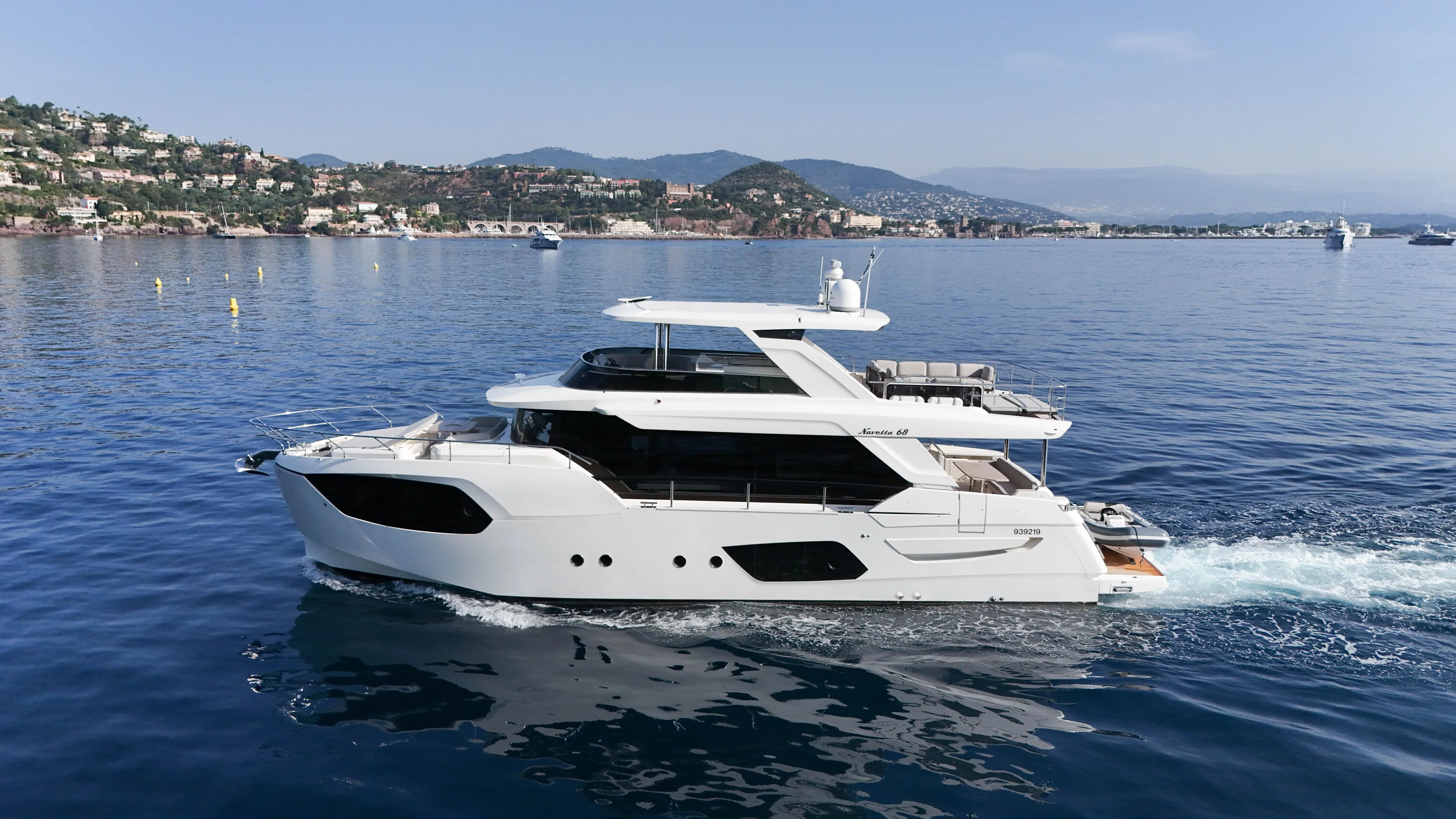  Yacht Photos Pics 2023 Absolute Navetta 68 yacht cruising on calm waters near a scenic coastline.