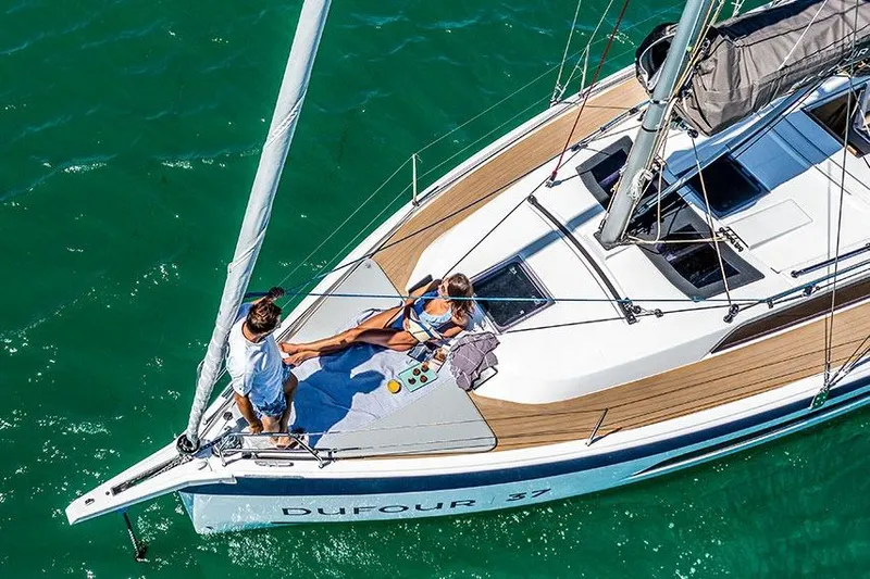  Yacht Photos Pics 2024 Dufour 37 sailboat with people relaxing on deck in sunny weather.