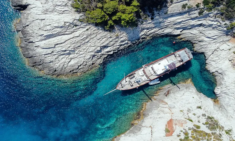 Corsario Yacht Photos Pics Aerial view of 2019 Custom RADEŽ d.d. Schooner anchored in a turquoise cove.