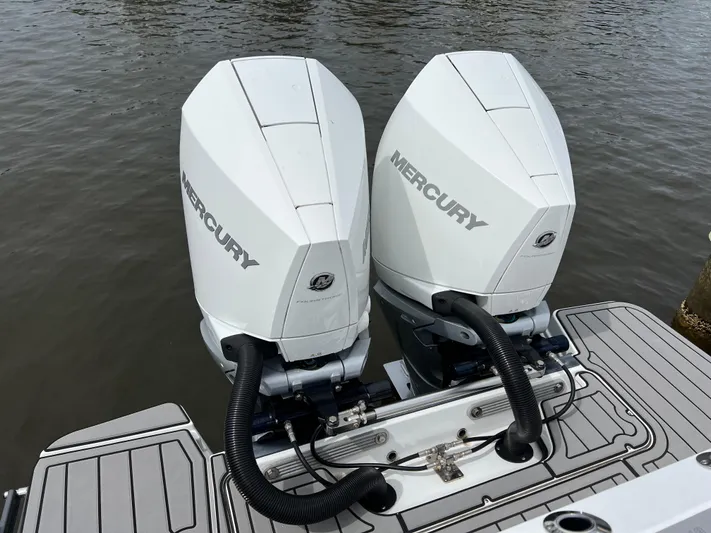 Blackfin Yacht Photos Pics Twin Mercury outboard engines on a 2023 Blackfin 272DC boat, docked on calm water.