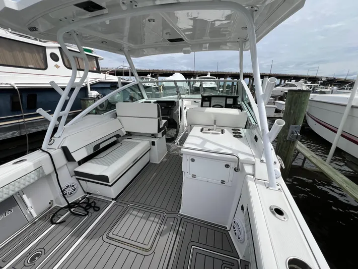 Blackfin Yacht Photos Pics 2023 Blackfin 272DC boat interior with seating and helm, docked at a marina.