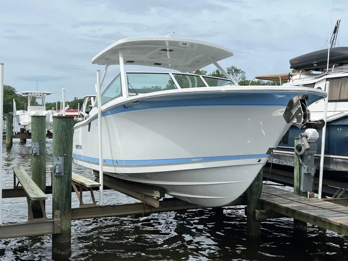 Blackfin Yacht Photos Pics 2023 Blackfin 272DC boat docked on a lift at a marina.