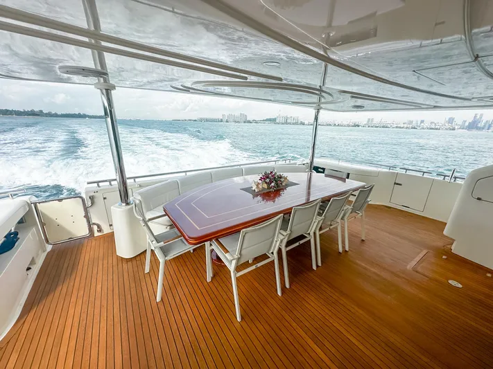 Eaglewings 3 Yacht Photos Pics Luxurious 2005 Custom Line 112 yacht deck with dining table, ocean view, and city skyline.